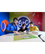 A man in a blue Everton fleece playing a board game with two children