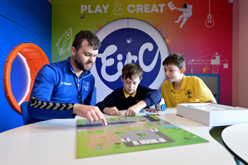 A man in a blue Everton fleece playing a board game with two children