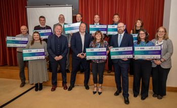 A group of people stood on a stage holding boards with pledges