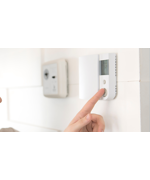 A thermostat on the wall being adjusted to increase the temperature